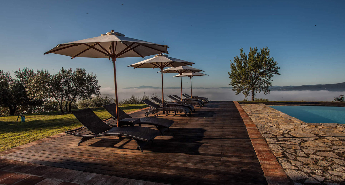 Castello La Leccia outdoor pool and patio with low hanging clouds in background