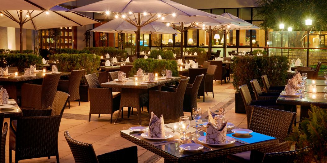InterContinental Jordan Hotel outdoor patio dining area with umbrella covered seating shown at night