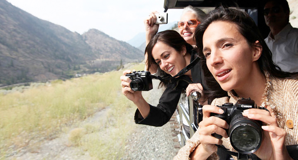 Guests on board the Rocky Mountaineer's viewing platform taking photographs of passing scenery
