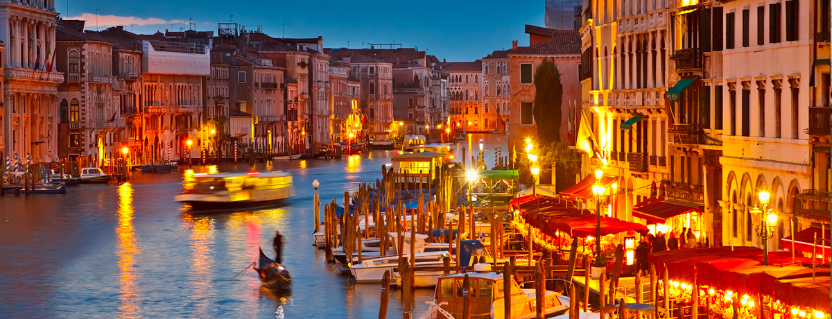 Street lights illuminating gondoliers along the Grand Canal at night