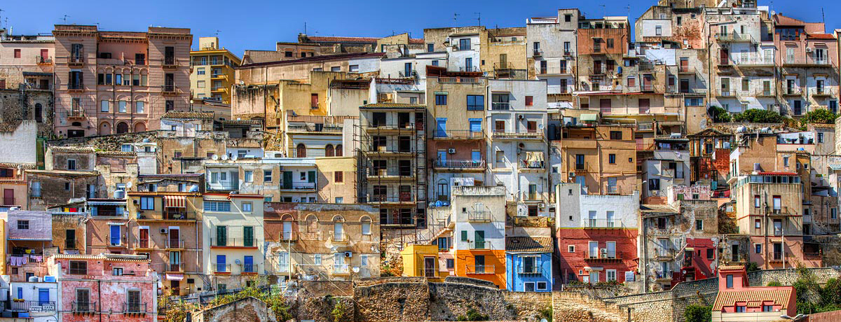 Colorful homes and building lining a harbor in Sicily