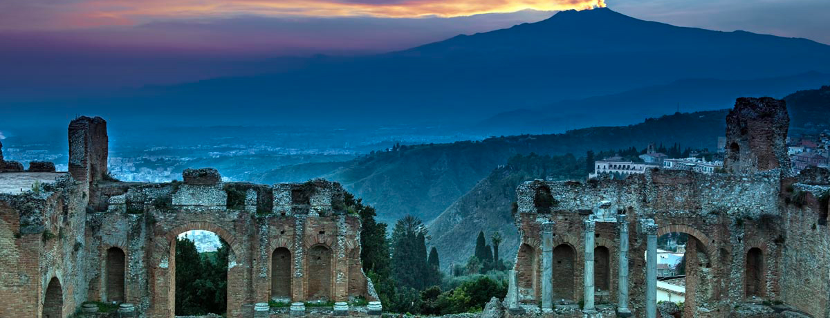 Ruins in Taormina at dusk with Mount Etna in background