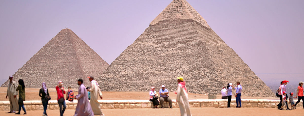 Pyramids in the background with people walking in the foreground