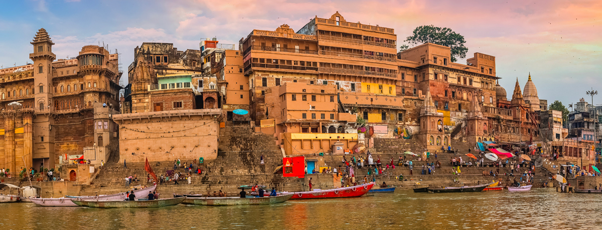 Panorama of Varanasi's ancient city architecture pictured from the water at sunset