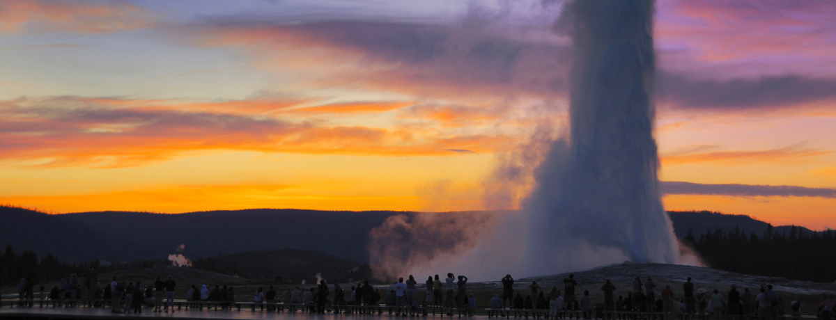 Old Faithful erupting during sunset