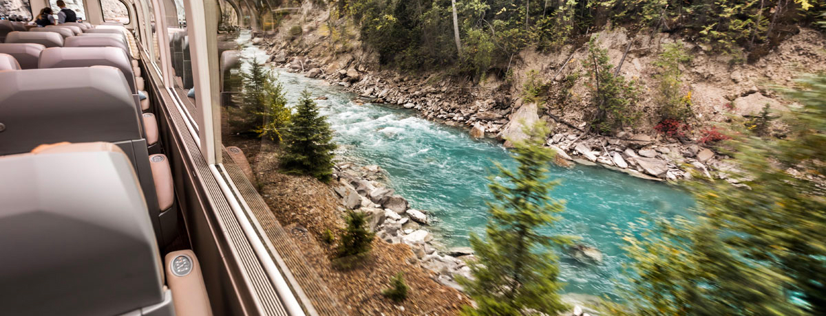 Rocky Mountaineer traveling aside a blue river