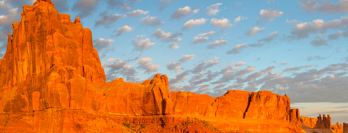 Puffy clouds floating over red cliffs at Arches National Park
