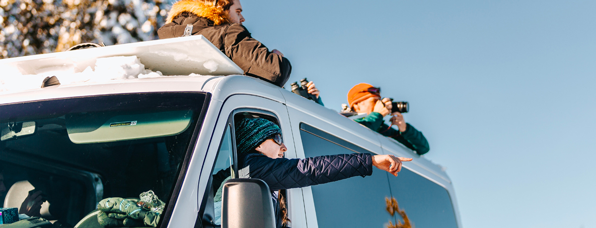 Spotters pointing to wildlife from Teton Science Schools touring snow van